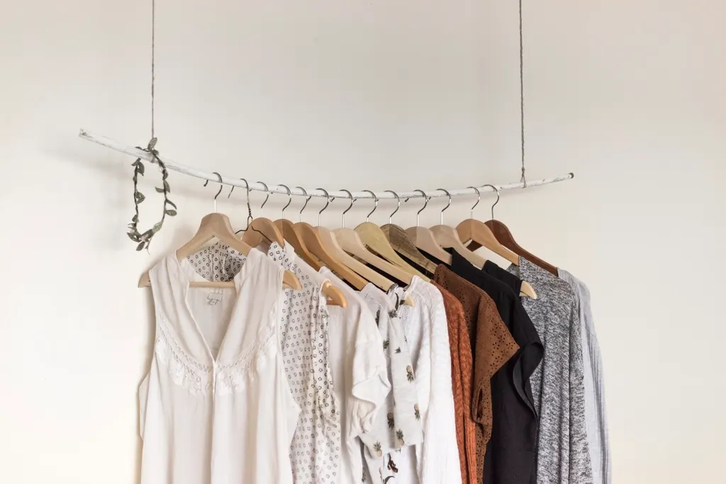 Neutral-toned shirts and dresses on matching hangers along a rail