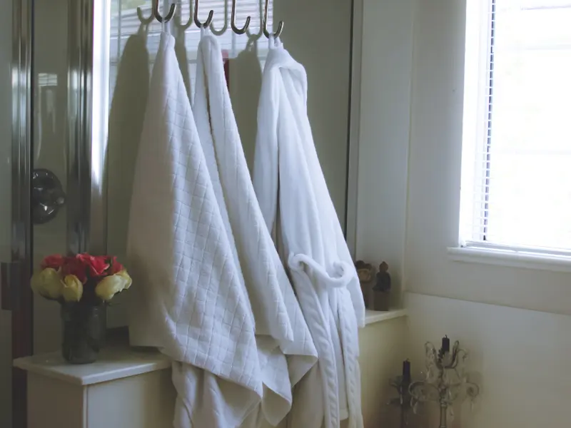White bathrobes hanging on hooks in a bright bathroom